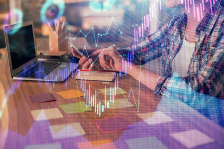 Double exposure of businesswoman hands typing on computer and forex graph hologram drawing....