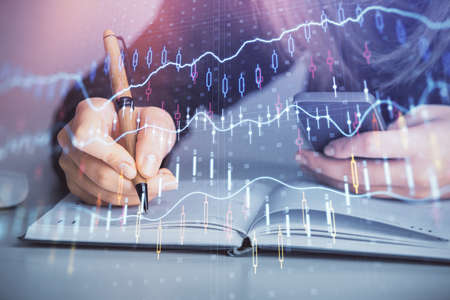Double exposure of businesswoman hands typing on computer and forex graph hologram drawing....