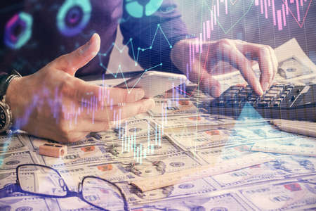 Double exposure of mans hands holding and using a digital device and forex graph drawing. Financial market concept.の写真素材