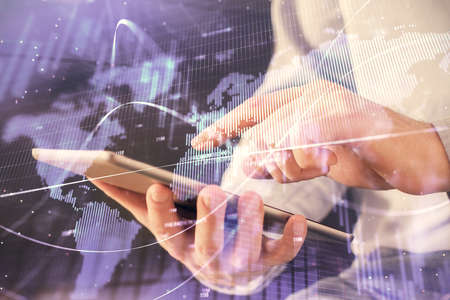 Double exposure of mans hands holding and using a digital device and forex graph drawing. Financial...
