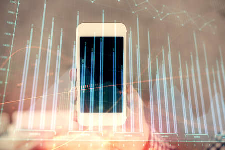 Double exposure of mans hands holding and using a digital device and forex graph drawing. Financial market concept.の写真素材