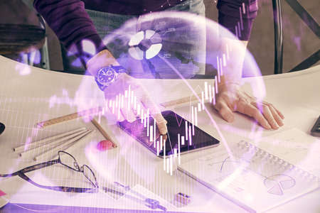 Double exposure of mans hands holding and using a digital device and forex graph drawing. Financial market concept.の写真素材
