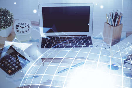 Double exposure of desktop with computer and world map hologram. International data network concept.の写真素材
