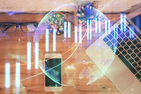 Double exposure of financial graph hologram over desktop with phone. Top view. Mobile trade platform...