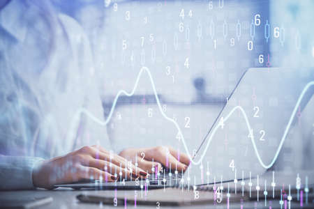 Double exposure of woman hands working on computer and forex graph hologram drawing. Financial...