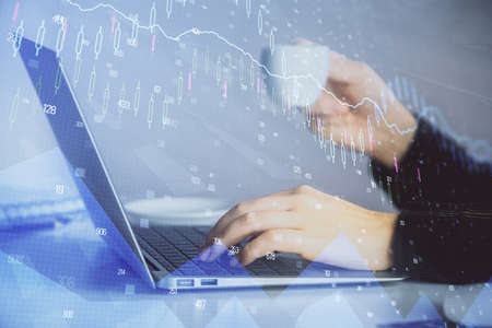 Double exposure of businesswoman hands typing on computer and forex graph hologram drawing....