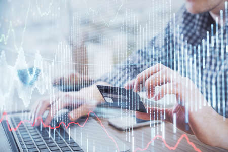 Double exposure of man hands holding a credit card and Forex graph drawing. Stock trading and digital fintech in Internet E-commerce concept.の写真素材
