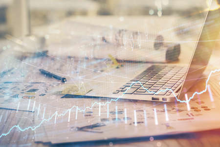 Stock market chart hologram drawn on personal computer background. Double exposure. Concept of investment.の写真素材