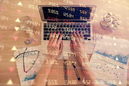 Double exposure of woman hands working on computer and forex graph hologram drawing. Top View. Financial analysis concept.の写真素材