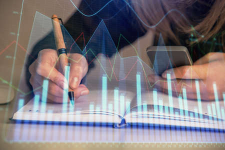 Double exposure of businesswoman hands typing on computer and forex graph hologram drawing....
