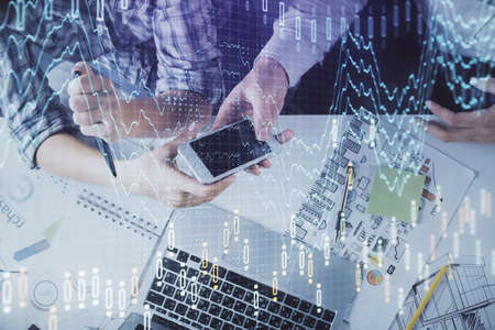 Double exposure of forex graph drawing and man and woman working together holding and using a mobile...