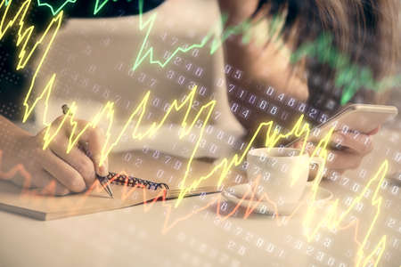 Double exposure of forex graph sketch hologram and woman holding and using a mobile device. Stock...
