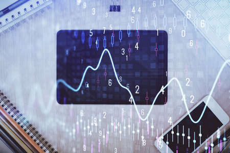 Double exposure of forex graph hologram over desktop with phone. Top view. Mobile trade platform...