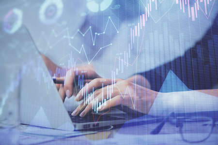 Multi exposure of woman hands typing on computer and financial graph hologram drawing. Stock market...