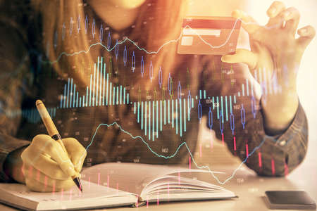 Multi exposure of woman on-line shopping holding a credit card and financial graph drawing. Stock...