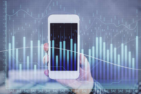 Double exposure of mans hands holding and using a digital device and forex graph drawing. Financial...