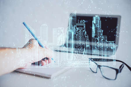 Abstract holographic city on mans hand writing notes background. Double exposure.