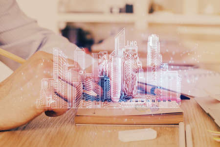Abstract holographic city on mans hand writing notes background. Multi exposure.