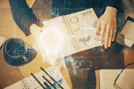 Bulb hologram over hands taking notes background. Concept of idea. Double exposureの写真素材