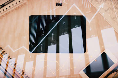 Double exposure of forex graph hologram over desktop with phone. Top view. Mobile trade platform...