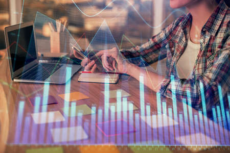 Double exposure of businesswoman hands typing on computer and forex graph hologram drawing....