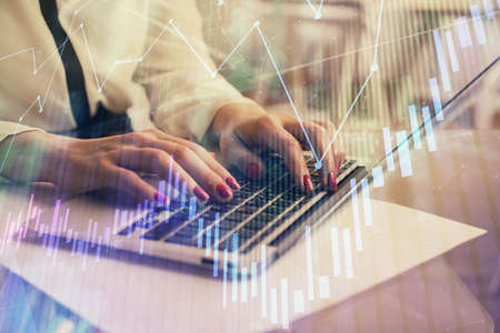 Multi exposure of woman hands typing on computer and financial graph hologram drawing. Stock market...