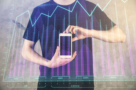 Double exposure of mans hands holding and using a digital device and forex graph drawing. Financial...