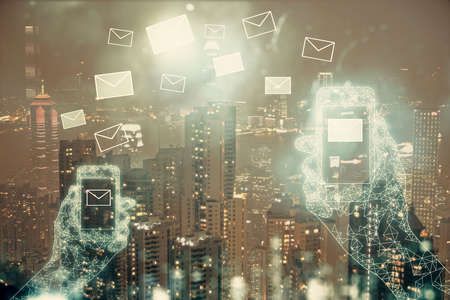 Double exposure of envelop hologram flying from gadget and city view background. Concept e-mail.の写真素材