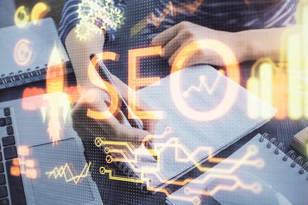 Multi exposure of womans hands making notes with SEO icon. Concept of Search engine optimization