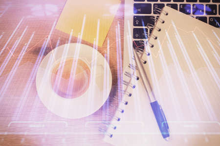 Double exposure of financial chart drawing over table background with computer. Concept of research and analysis. Top view.の写真素材