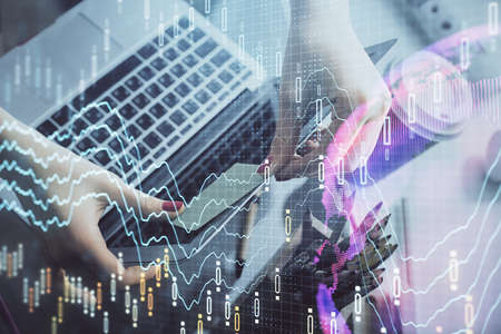 Double exposure of businesswoman hands typing on computer and financial graph hologram drawing....