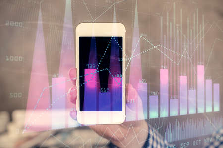 Double exposure of mans hands holding and using a digital device and forex graph drawing. Financial market concept.の写真素材