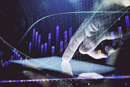 Double exposure of mans hands holding and using a digital device and forex graph drawing. Financial...