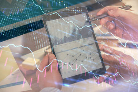 Double exposure of mans hands holding and using a phone and financial chart drawing. Market analysis...