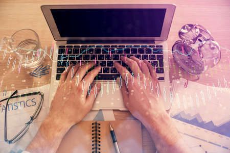Double exposure of mans hands typing over laptop keyboard and forex chart hologram drawing. Top view. Financial markets concept.の写真素材
