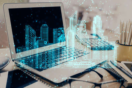 Desktop computer background in office and big town buildings hologram drawing. Double exposure....