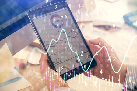 Double exposure of mans hands holding and using a phone and financial graph drawing. Analysis...