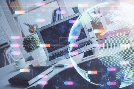 Double exposure of desktop with computer and world map hologram. International data network concept.