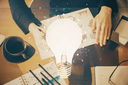 Bulb hologram over hands taking notes background. Concept of idea. Double exposureの写真素材