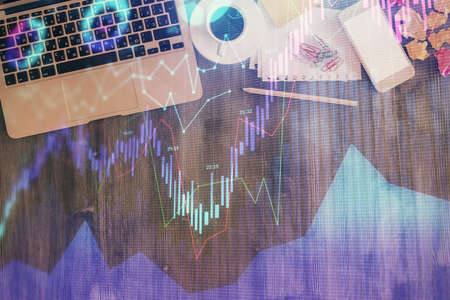 Financial market graph and top view computer on the desktop background. Double exposure. Investment concept.の写真素材