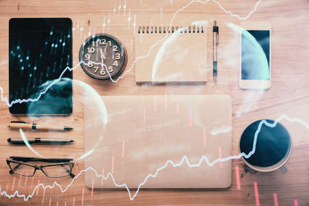 Double exposure of forex graph hologram over desktop with phone. Top view. Mobile trade platform concept.の写真素材