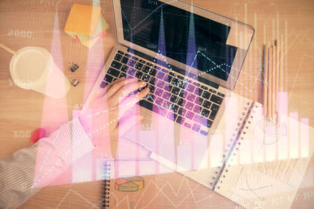 Double exposure of mans hands typing over computer keyboard and forex graph hologram drawing. Top view. Financial markets concept.の写真素材