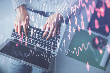 Multi exposure of woman hands working on computer and forex chart hologram drawing. Top View....