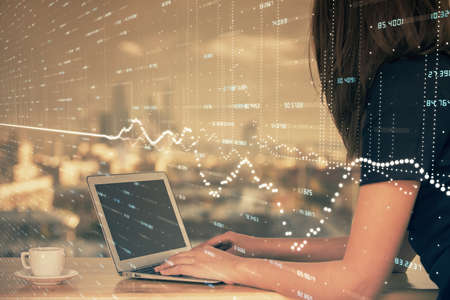 Double exposure of businesswoman hands typing on computer and forex chart hologram drawing....