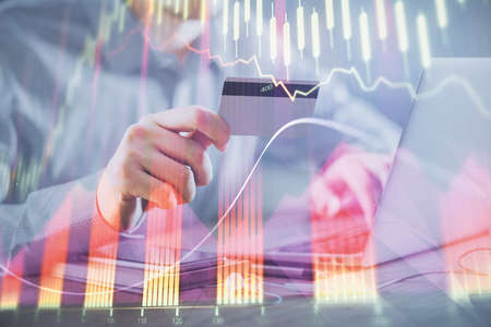 Double exposure of man hands holding a credit card and Forex graph drawing. Stock trading and...
