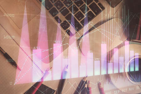 Double exposure of financial chart drawing over table background with computer. Concept of research...