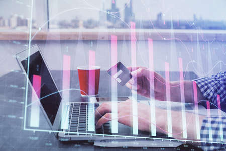 Double exposure of man hands holding a credit card and Forex graph drawing. Stock trading and digital fintech in Internet E-commerce concept.の写真素材