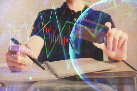 Double exposure of man hands holding a credit card and Forex graph drawing. Stock trading and...