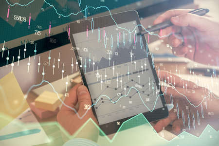 Double exposure of mans hands holding and using a phone and financial chart drawing. Market analysis...