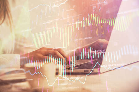 Double exposure of woman hands working on computer and forex graph hologram drawing. Financial...